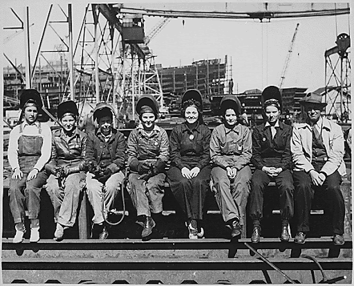 Black and white photograph showing a line up of women welders sitting together 